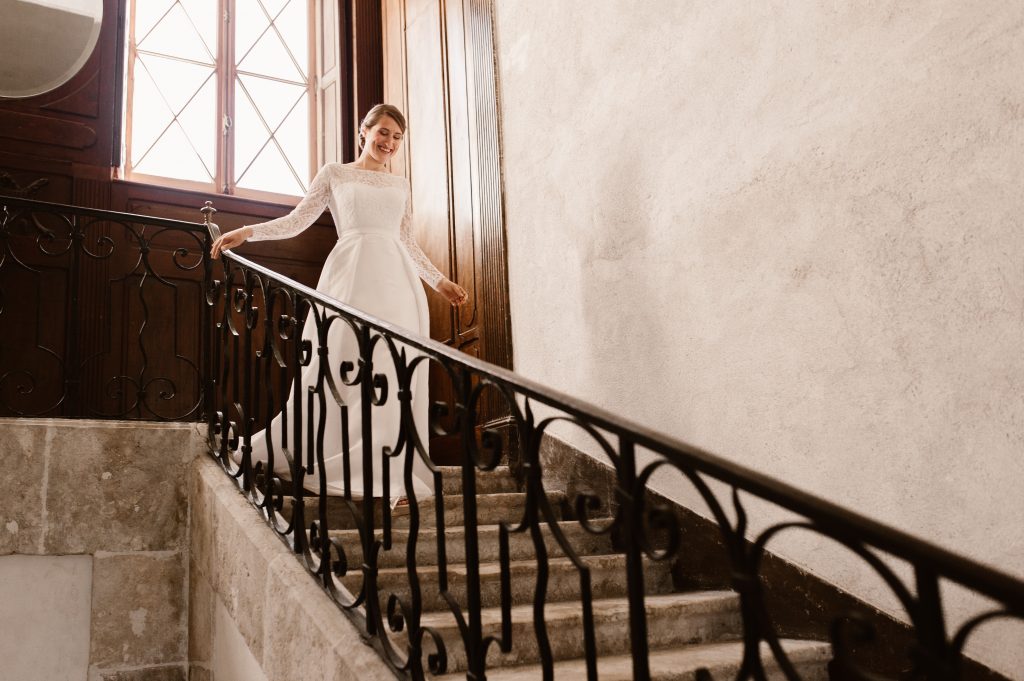 La mariée descend l'escalier pour découvrir son mari