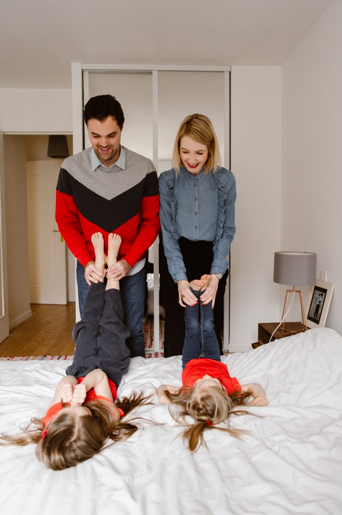 Parents tenant les pieds de leurs filles, allongées sur le lit