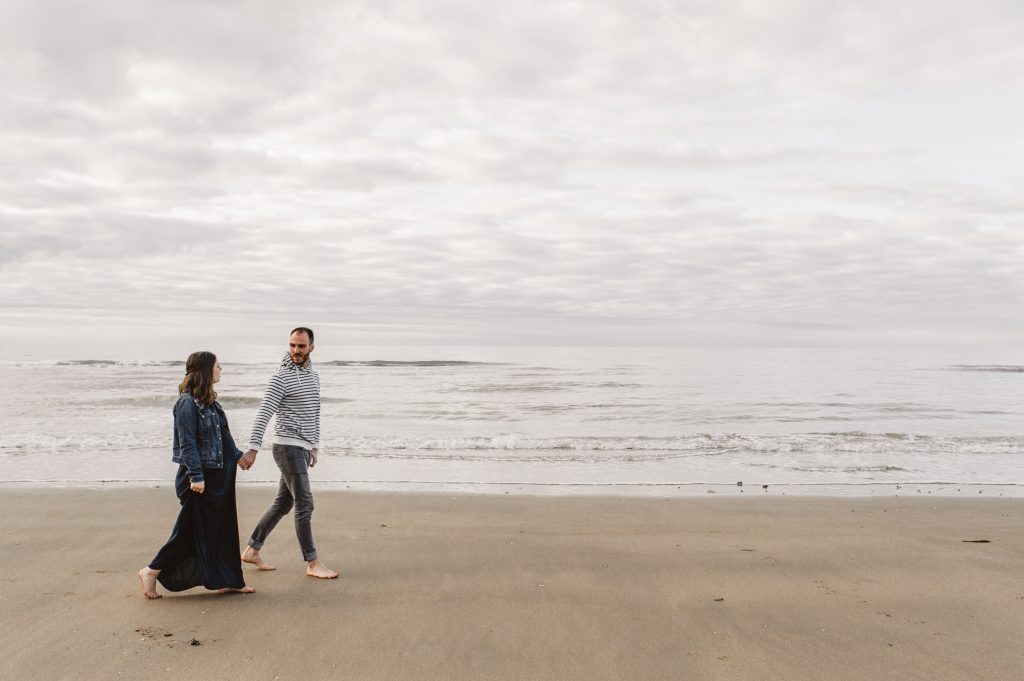 Couple marchant sur le sable d'une plage en Normandie, en attendant bébé