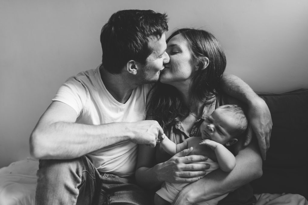 Baiser des parents avec leur nourrisson dans les bras Portrait naissance Paris